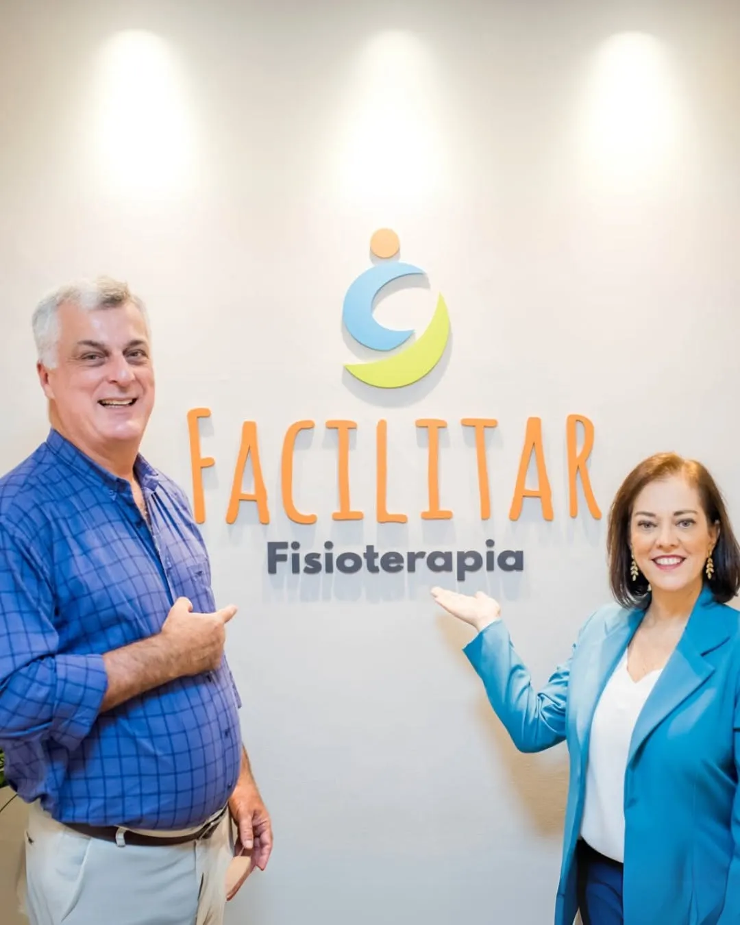 Sócios da Facilitar Fisioterapia em frente à logo da clínica